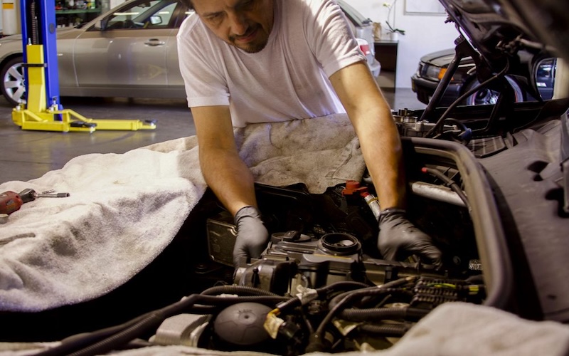Mechanic servicing a car at the BMW Guy shop.